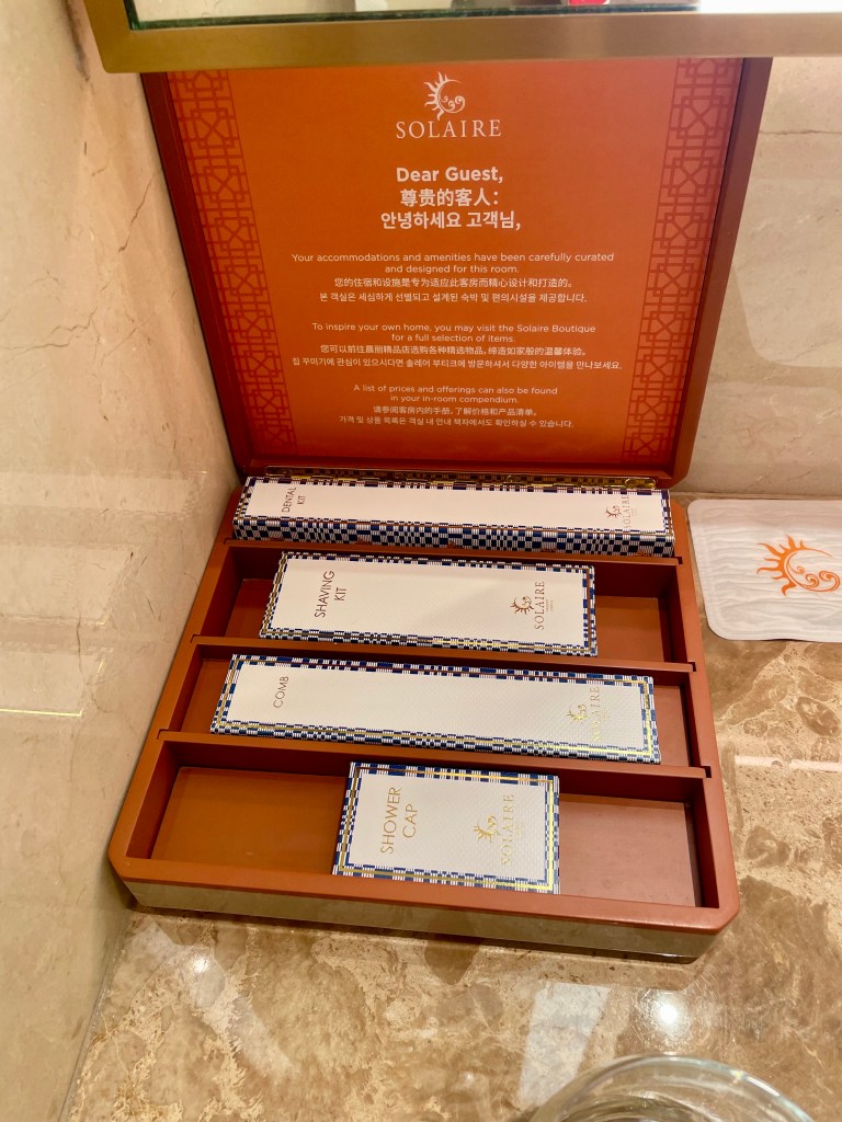 Detailed view of guest bathroom amenities at Solaire Resort North, including shaving kit, comb, shower cap, and a message from the hotel.