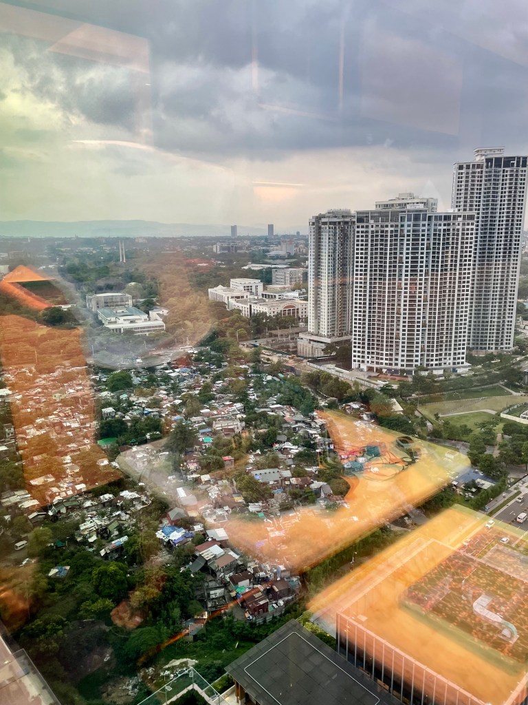 High-rise cityscape view from Solaire Resort North, showing a mix of modern condominiums and underdeveloped urban areas in Quezon City.